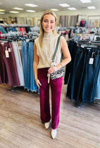 Solid sleeveless mock neck sweater knit top featuring cable knit texture.