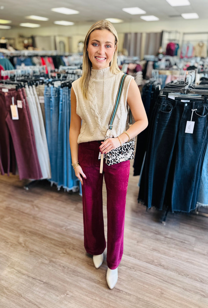 Solid sleeveless mock neck sweater knit top featuring cable knit texture.