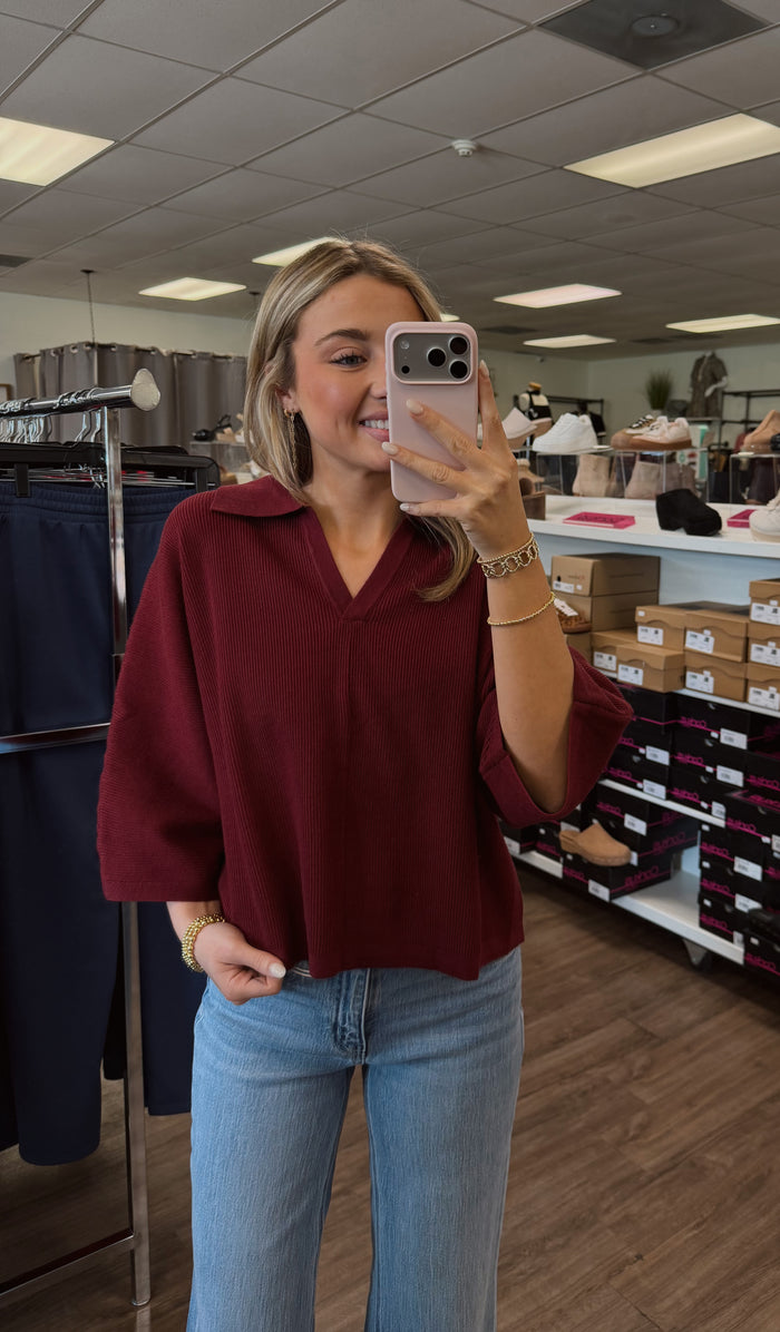 Solid 3/4 sleeve knit top featuring open V-neck collar