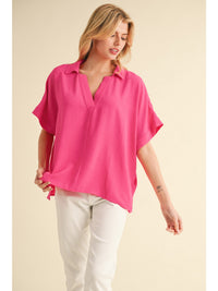 Solid top with open collared neck, short dolman sleeves, band cuffs, and vented hemline.