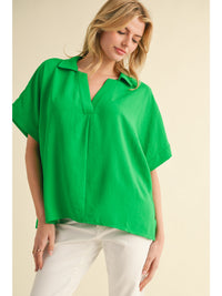 Solid top with open collared neck, short dolman sleeves, band cuffs, and vented hemline.