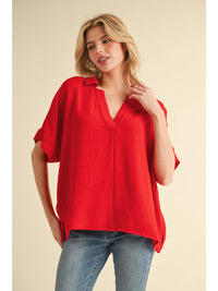Solid top with open collared neck, short dolman sleeves, band cuffs, and vented hemline.