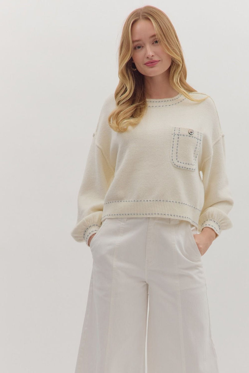 Solid long sleeve sweater knit top featuring contrast blanket stitch accents