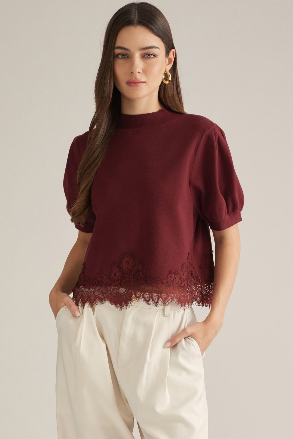 Solid short puff sleeve sweater top with a mock neck. Lace trim detail at hem.