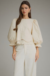 Solid ¾ balloon sleeve top with a round neckline and lace trim detail at hem