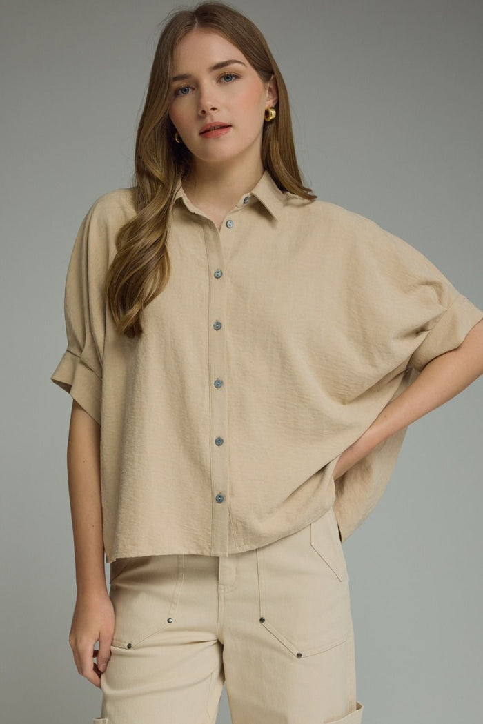 Solid short dolman sleeve top featuring a button closure at front